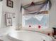 Oval soaking tub, window with sheer curtains, and decorative candles at 17852 Fancy Ln, Hudson, FL 34667