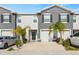 Two story townhome with gray siding, two car garage, and palm trees at 34395 Sorrel Mint Dr, Wesley Chapel, FL 33543