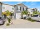 Two story townhome with gray siding, two car garage, and palm trees at 34395 Sorrel Mint Dr, Wesley Chapel, FL 33543