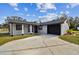 Newly renovated home with gray exterior, black garage door, and landscaping at 516 Highview N Cir, Brandon, FL 33510