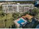 Aerial view of condo building, pool, and surrounding landscape at 100 Oakmont Ln # 602, Belleair, FL 33756