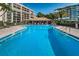 Community pool with lounge chairs and building view at 100 Oakmont Ln # 602, Belleair, FL 33756