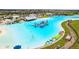 Aerial view of a resort-style community with a crystal lagoon, water activities, and sandy beach at 16961 Oval Rum Dr, Wimauma, FL 33598