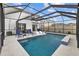 Luxury pool with covered patio, lounge chairs, and modern design at 16961 Oval Rum Dr, Wimauma, FL 33598