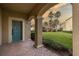 Covered front porch with teal door and brick flooring, overlooking a grassy yard at 17533 Stinchar Dr, Land O Lakes, FL 34638