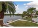 Spacious backyard with water access, dock, lush landscaping, and palm trees at 4536 Heavens Way, New Port Richey, FL 34652