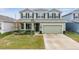 Two-story house with green exterior, two-car garage, and landscaped lawn at 7878 Greenway Ave, Wesley Chapel, FL 33544