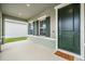 Covered front porch with green door and welcome mat at 7878 Greenway Ave, Wesley Chapel, FL 33544