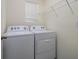 Bright laundry room with Whirlpool washer and dryer and overhead shelving at 9228 Forge Breeze Loop Loop, Wesley Chapel, FL 33545