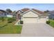 Tan house with brown roof, two-car garage, and landscaped yard at 14638 Strathglass Dr, Hudson, FL 34667