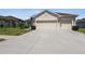 Tan house with three car garage and landscaped yard at 14638 Strathglass Dr, Hudson, FL 34667