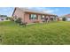 Rear view of tan house showcasing a well-manicured lawn and landscaping at 1809 Wolf Laurel Dr, Sun City Center, FL 33573