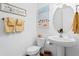 Clean bathroom with pedestal sink, toilet and beach-themed artwork at 19915 Gulf Blvd # 303, Indian Shores, FL 33785