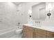 Bathroom featuring white tile, white walls, quartz countertop with wood cabinets, and brass finishes at 3640 15Th N St, St Petersburg, FL 33704