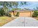 House exterior featuring orange walls, a two-car garage, and a well-maintained lawn at 4020 Concord Way, Plant City, FL 33566