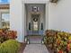 Front entry with gray door, lanterns, and landscaping at 821 Forest Glen Ct, Palm Harbor, FL 34683