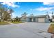 Ranch style home with a large driveway, mature trees, and a well-maintained lawn at 9100 52Nd N Way, Pinellas Park, FL 33782