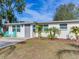 Updated bungalow with gray door, teal chairs, and a landscaped lawn at 10463 118Th Ave, Largo, FL 33773