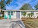 Updated bungalow with gray door, teal chairs, and a landscaped lawn at 10463 118Th Ave, Largo, FL 33773