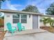 Updated bungalow with gray door, teal chairs, and a landscaped lawn at 10463 118Th Ave, Largo, FL 33773