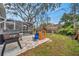 Spacious backyard with patio, screened enclosure, playset, and mature trees at 1753 Lucas Dr, Clearwater, FL 33759