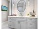 Elegant bathroom vanity with gray cabinets and a large round mirror at 2623 S Parkview St, Tampa, FL 33629