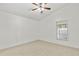 Bright bedroom features neutral carpet, a ceiling fan, and natural light from the window at 28643 Seashell Ct, Wesley Chapel, FL 33545