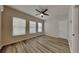 Bright bedroom with wood-look flooring, ceiling fan, and multiple windows at 29325 Birds Eye Dr, Wesley Chapel, FL 33543