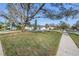 Single-story house with well-manicured front lawn, tropical trees and hardscape walkway and driveway at 3075 Rosery Ne Rd, Largo, FL 33771