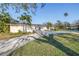 Single-story house with well-manicured front lawn, tropical trees and hardscape walkway and driveway at 3075 Rosery Ne Rd, Largo, FL 33771