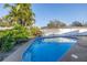 Relaxing backyard pool with clear blue water, surrounded by a concrete patio, lush plants and a privacy fence at 3075 Rosery Ne Rd, Largo, FL 33771