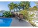 A view of the inground pool and the outdoor table and chairs, surrounded by green plants and a white fence at 3075 Rosery Ne Rd, Largo, FL 33771