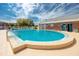 Community swimming pool with a rounded shape and brick building nearby at 3475 41St S Ter # 215, St Petersburg, FL 33711