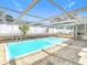 A clear, enclosed pool with ladder entry points surrounded by tiled and gravel outdoor space at 4024 Jib Sail Ct, New Port Richey, FL 34652