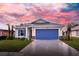 One-story home with blue garage door and landscaped yard; sunset in the background at 425 Rose Apple Cir, Port Charlotte, FL 33954