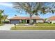 Single-story home with a tile roof, landscaping, and a large tree in the front yard at 5809 Cruiser Way, Tampa, FL 33615