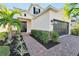 Front entry and walkway with brick pavers, landscaping, and a two-car garage at 6137 Voyagers Pl, Apollo Beach, FL 33572