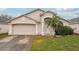 One-story house with a two-car garage, palm tree, and front yard at 6325 Chapel Pines Blvd, Wesley Chapel, FL 33545