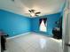 Bright bedroom with blue walls, tile floors, and ceiling fan at 1447 Coble Rd, Spring Hill, FL 34608