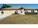 Tan house with a brown roof, attached garage, and landscaped yard at 1447 Coble Rd, Spring Hill, FL 34608