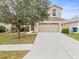 Two-story house with beige exterior, two-car garage, and landscaped lawn at 17608 Glenapp Dr, Land O Lakes, FL 34638