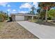 Single-story home with a gray exterior, long driveway, and palm trees at 18292 Robinson Ave, Port Charlotte, FL 33948