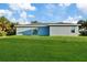 Rear view of a single-story home showcasing a sliding glass door and spacious yard at 18400 Tulane Ave, Port Charlotte, FL 33954