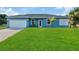 Newly constructed home with light blue exterior, white garage door, and a landscaped lawn at 18400 Tulane Ave, Port Charlotte, FL 33954