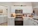 Modern kitchen with white cabinets, stainless steel appliances and a breakfast bar at 2028 Acadia Greens Dr, Sun City Center, FL 33573