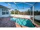 Screened-in pool with brick patio and white fence, surrounded by green trees at 2930 Swan Cir, Dunedin, FL 34698