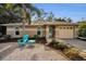 Tan house with teal door, gravel driveway, and landscaping at 663 Athens St, Dunedin, FL 34698