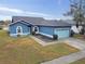 One-story blue house with a pond view, a light blue garage door, and a well-maintained lawn at 1330 Monte Lake Dr, Valrico, FL 33596