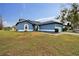 One-story blue house with a pond view, a light blue garage door, and a well-maintained lawn at 1330 Monte Lake Dr, Valrico, FL 33596