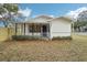 White house with a covered porch, fenced yard, and well-manicured landscaping at 1424 E Bougainvillea Ave, Tampa, FL 33612